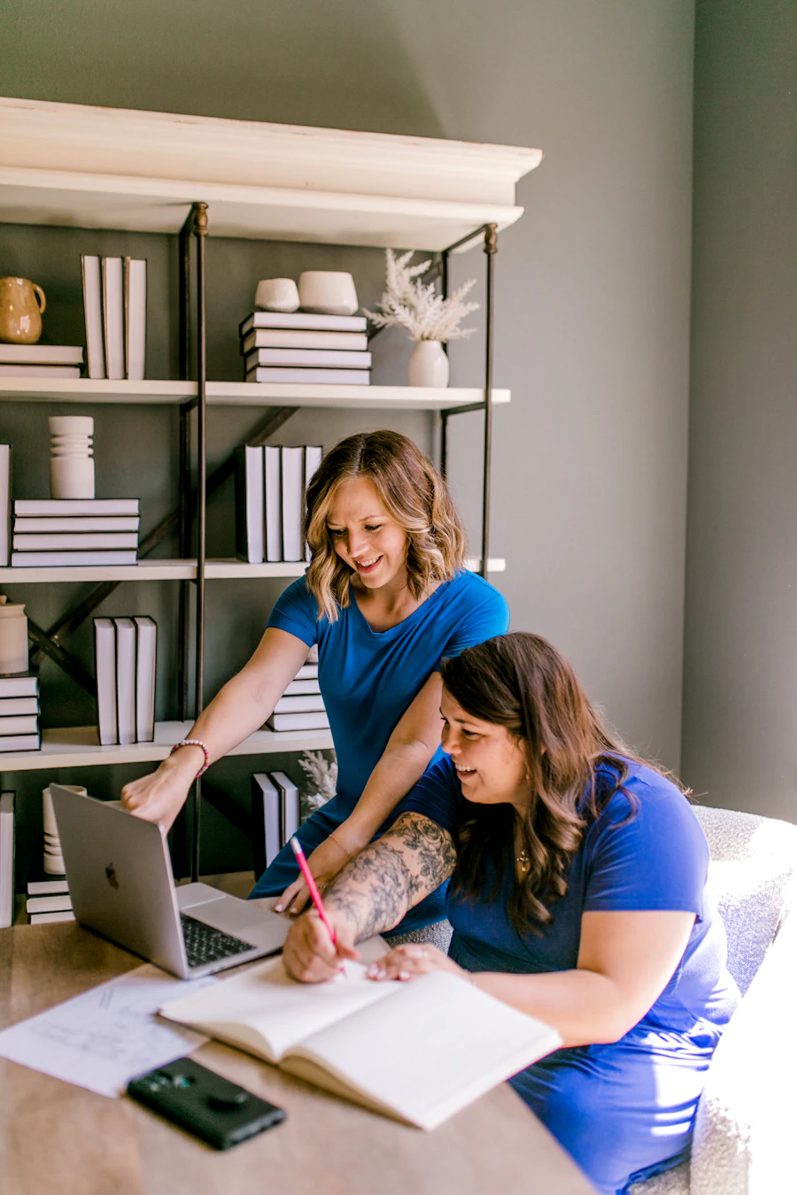 Duas mulheres numa aula, sentadas a uma mesa com livros e cadernos